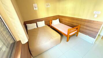 Quarto com uma cama, um banco de madeira e duas imagens penduradas na parede.