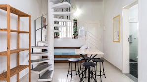 Une cuisine avec un escalier en bois, une table à manger avec des tabourets et une vue sur la salle de bain.
