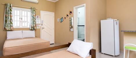 A room with two beds, a white refrigerator, a bathroom, and a small stool.