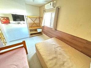 A room with two beds, a TV, a shelf unit, and a window with curtains. - Recanto Maranduba (Ubatuba)