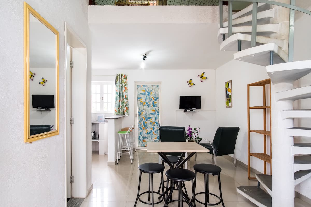 A modern interior with a dining area, kitchen, and a spiral staircase.