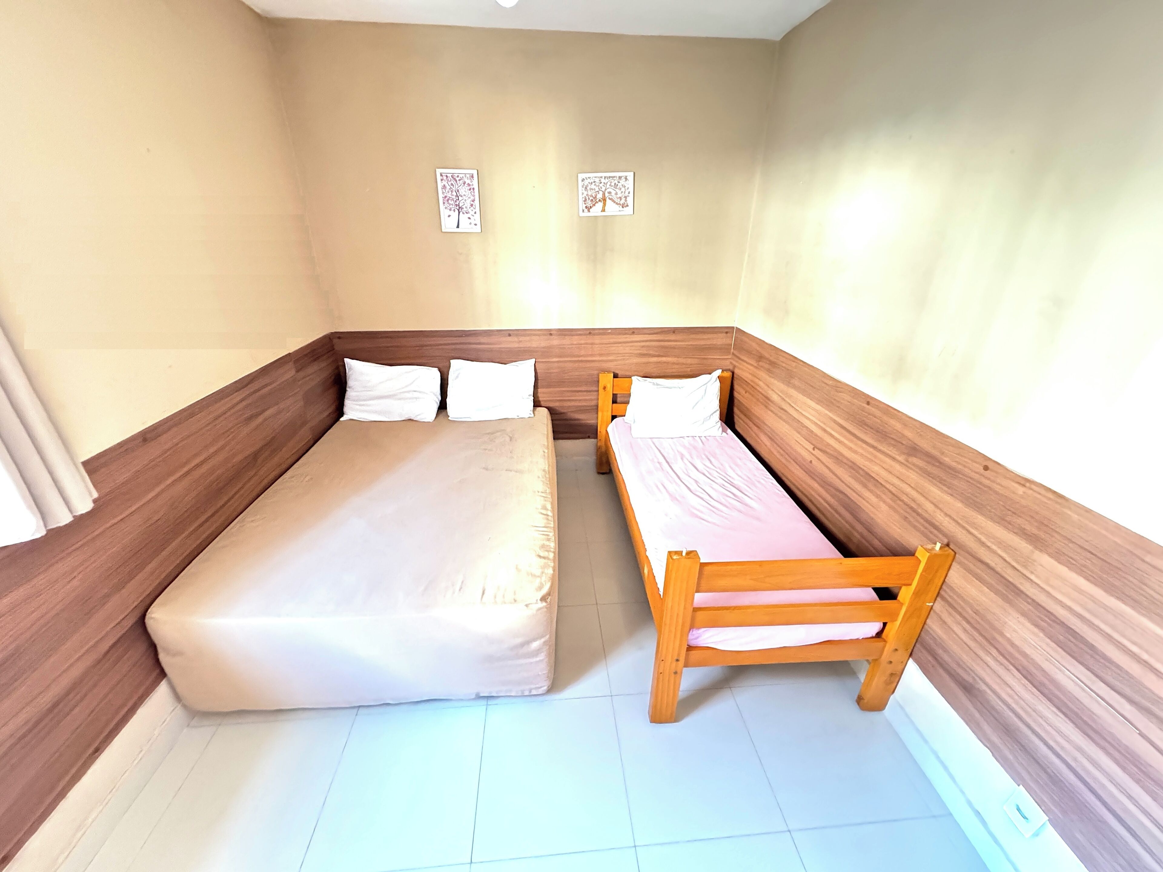 Un alojamiento pequeño y de una sola habitación con una cama, un banco y dos cuadros colgados.