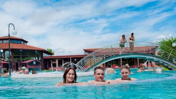 A swimming pool area with a covered bridge, a pavilion, and a building with a red roof. - Hotel & Restaurant Engel (Herbertingen)