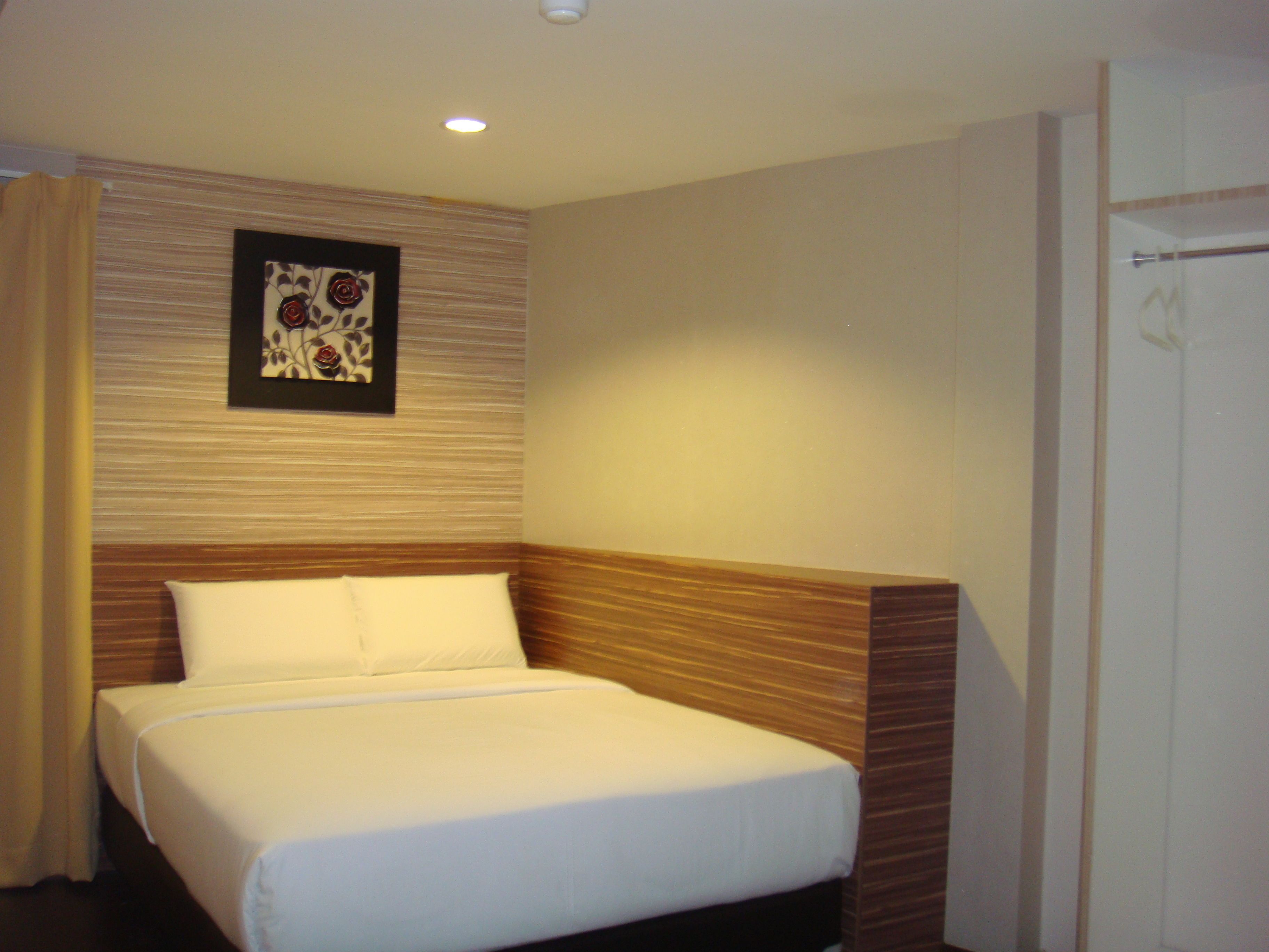A hotel room with a bed, a wooden headboard, a wall-mounted artwork, and a door.