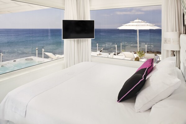Ein Schlafzimmer mit einem großen Bett, einem Fernseher und Blick auf den Ozean.