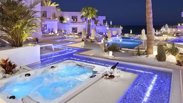 A modern hotel with a rooftop pool, a hot tub, and lounge areas.