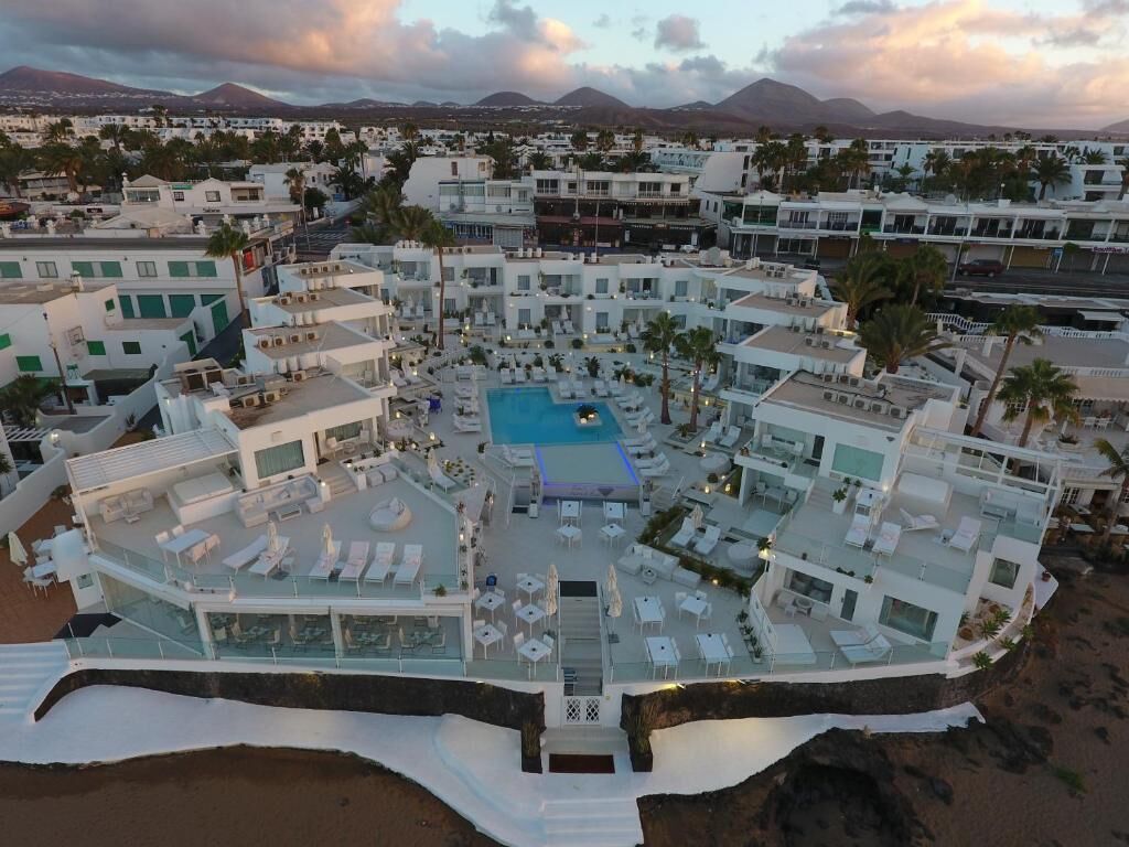 A resort with multiple buildings, a central pool, and a beach area.