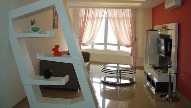 A modern living room with a glass coffee table, a flat-screen TV, and a unique white shelving unit. - Duta Hotel & Residence (Kuala Lumpur)