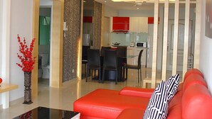 A modern living room with a red sofa, a glass coffee table, and a decorative vase. - Duta Hotel & Residence (Kuala Lumpur)