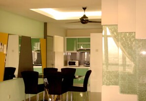 A modern kitchen with a microwave, stove, and dining area with chairs. - Duta Hotel & Residence (Kuala Lumpur)