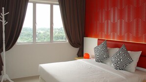 A hotel room with a large bed, a view of greenery through the window, and a red textured wall. - Duta Hotel & Residence (Kuala Lumpur)