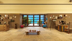 A spacious room with a brick wall, large windows, a desk, chairs, and a coffee table. - Club Mahindra Kanha (Bichhiya)