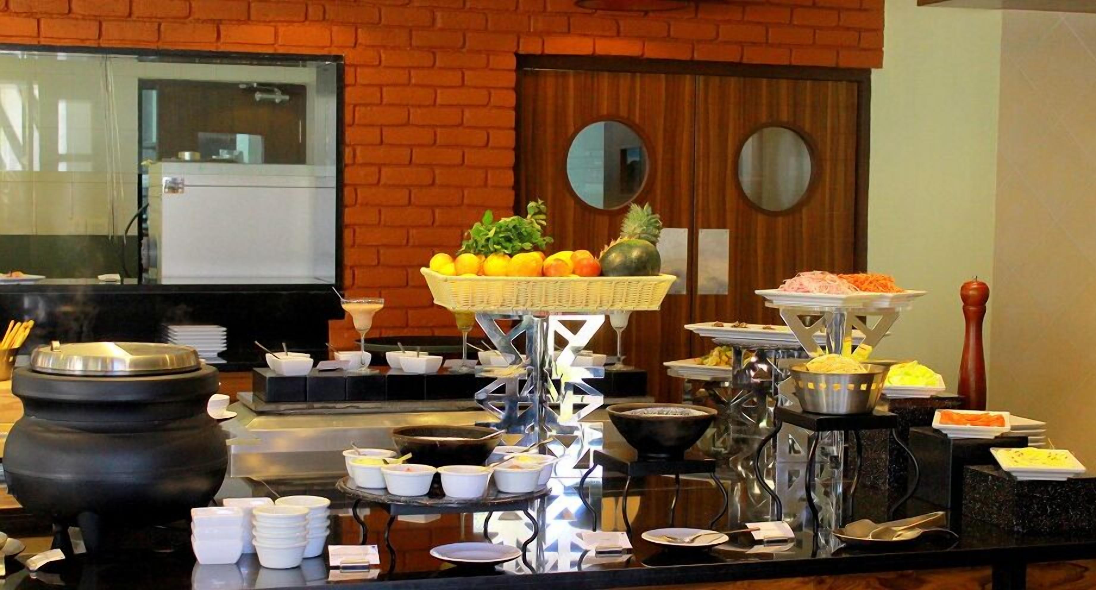 A buffet setup with various food items and a brick wall background.