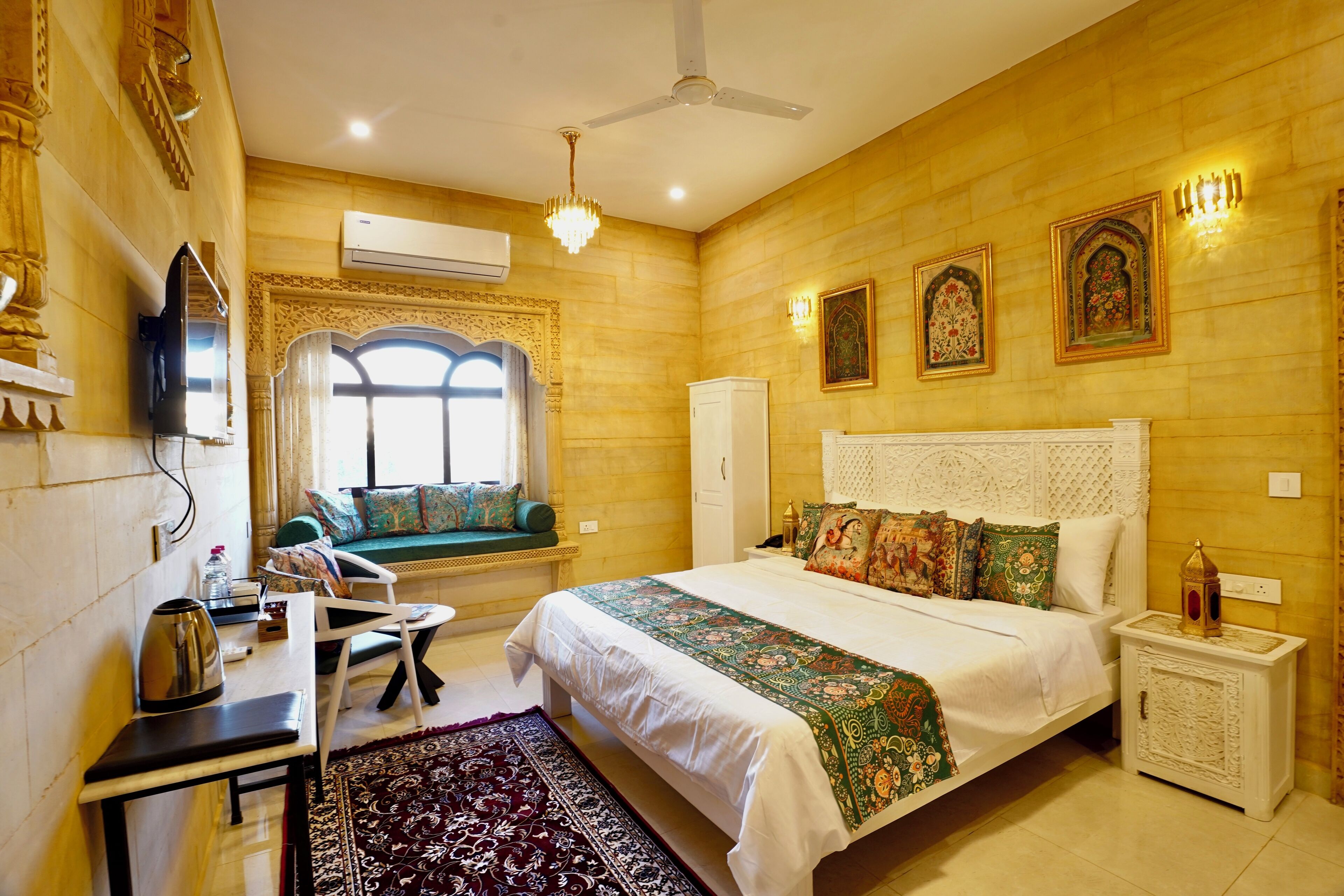 A hotel room with a bed, a desk, a chair, a window, and a ceiling fan.