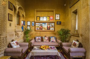 A traditional interior with a sofa set, framed certificates, and a central table with a floral arrangement.