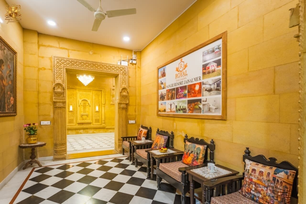 Un'hall di un hotel con pavimento a scacchi, una reception e una bacheca informativa a parete.
