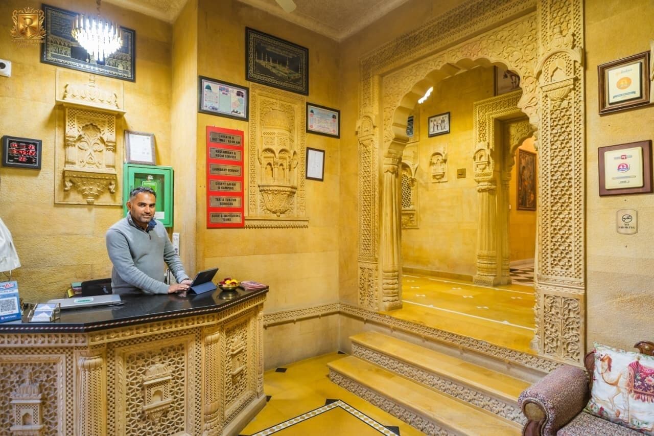 An ornate reception area with a receptionist desk, framed certificates, and intricate wall carvings.