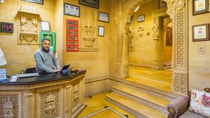 Un hall d’accueil somptueux, avec un comptoir de réception, des certificats encadrés et des sculptures complexes ornant les murs.