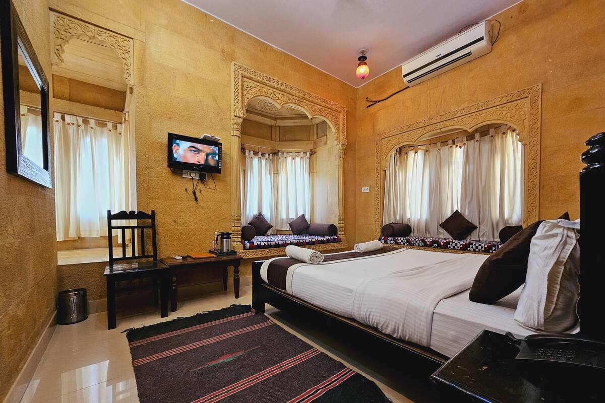 Une chambre d’hôtel avec un lit, un bureau, une télévision et une fenêtre avec des rideaux.
