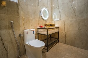 Un baño con inodoro, tocador con espejo y ducha.