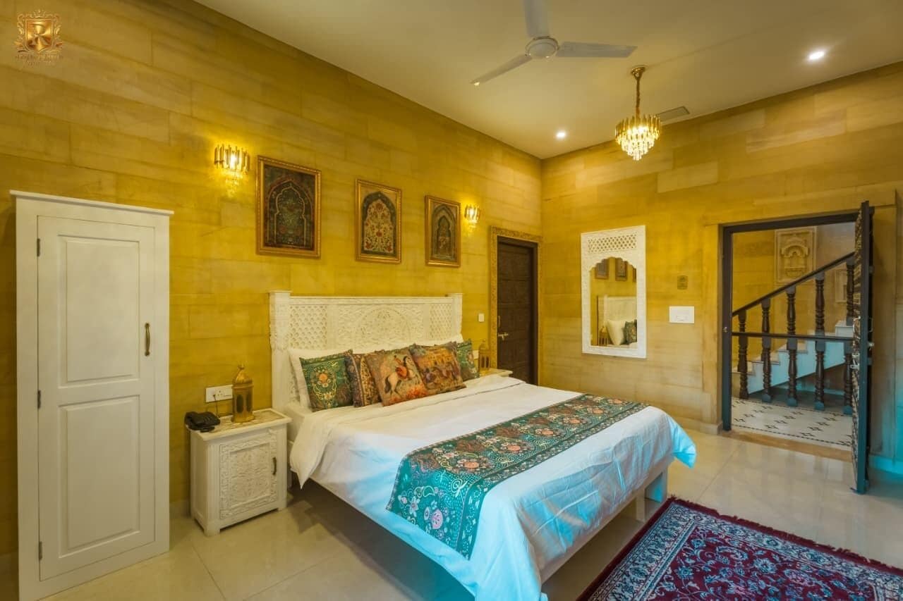A bedroom with a bed, nightstand, wall-mounted lights, and a staircase.