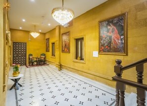 A hallway with a patterned floor, a chandelier, a staircase, and a painting on the wall. - Hotel Royal Haveli (Jaisalmer)
