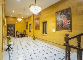 Un pasillo con piso estampado, una araña de cristal, una escalera y un cuadro en la pared.