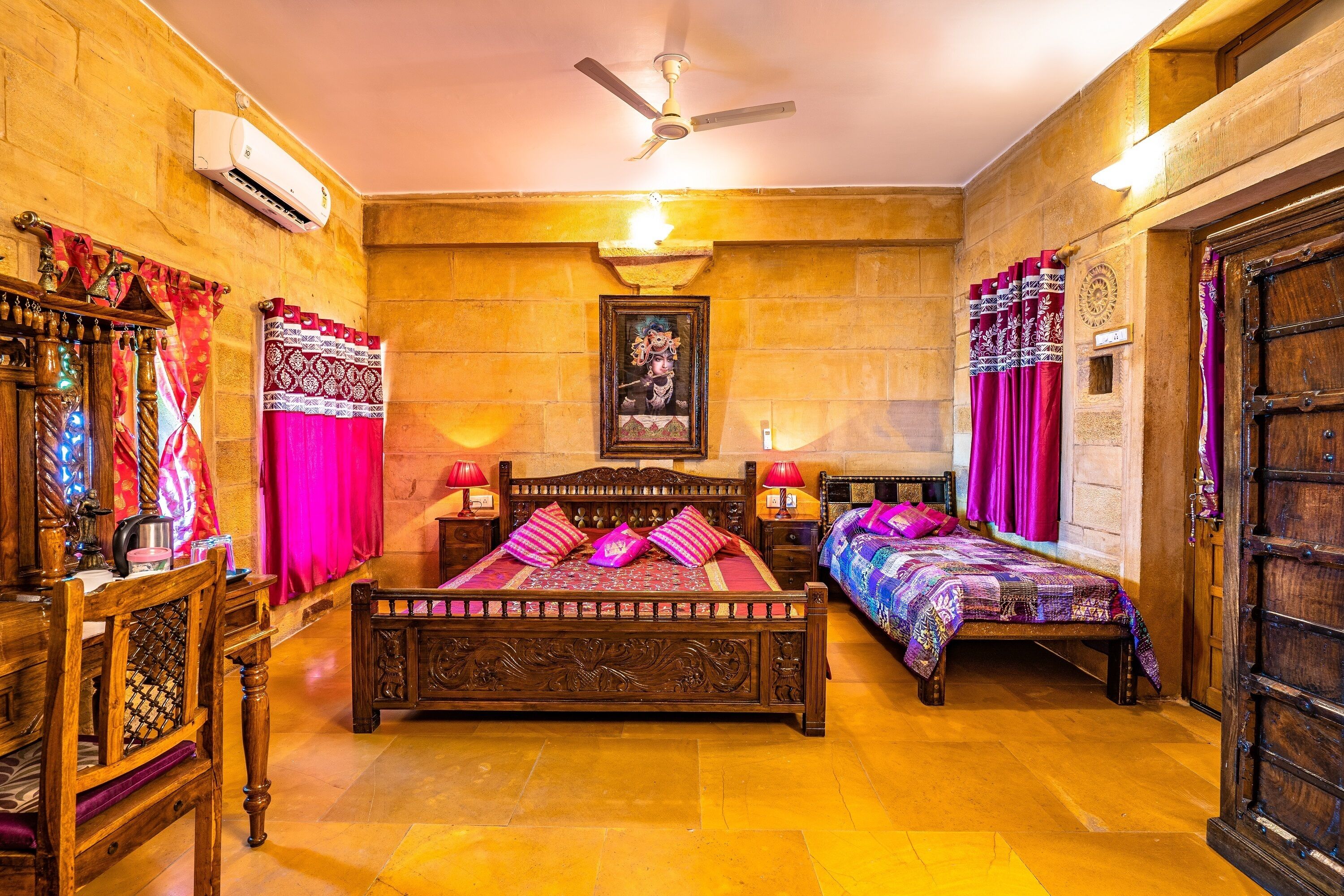 A traditional room with a wooden bed, two bedside tables, a wooden wardrobe, and a ceiling fan.