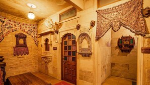 A traditional room with a wooden door, intricate wall decorations, and a welcome mat. - Hotel Garh Jaisal Haveli (Jaisalmer)