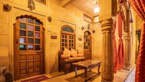 A traditional interior with wooden doors, a bench, and a welcome mat. - Hotel Garh Jaisal Haveli (Jaisalmer)
