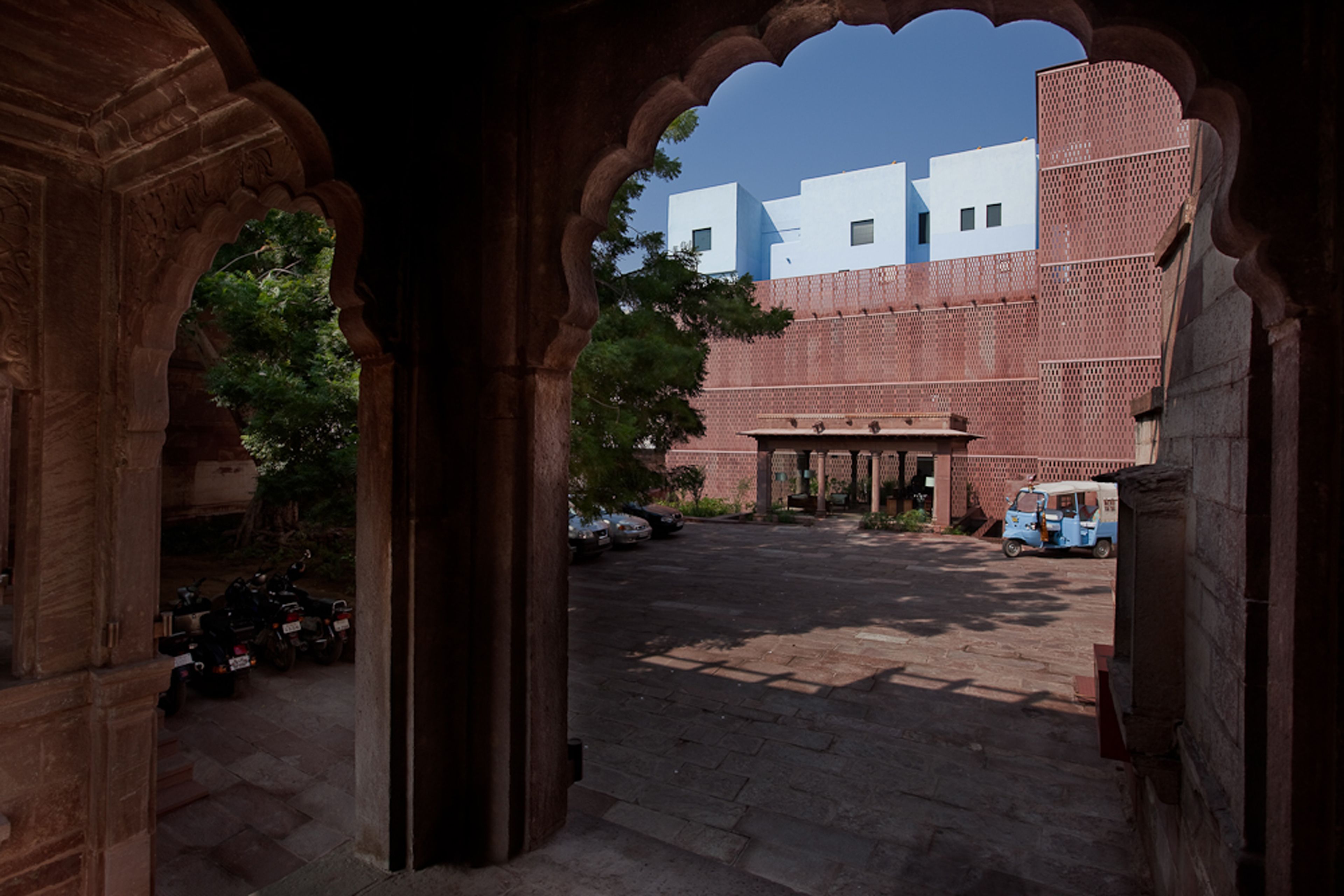 An arched doorway leading to a courtyard with a building in the background.