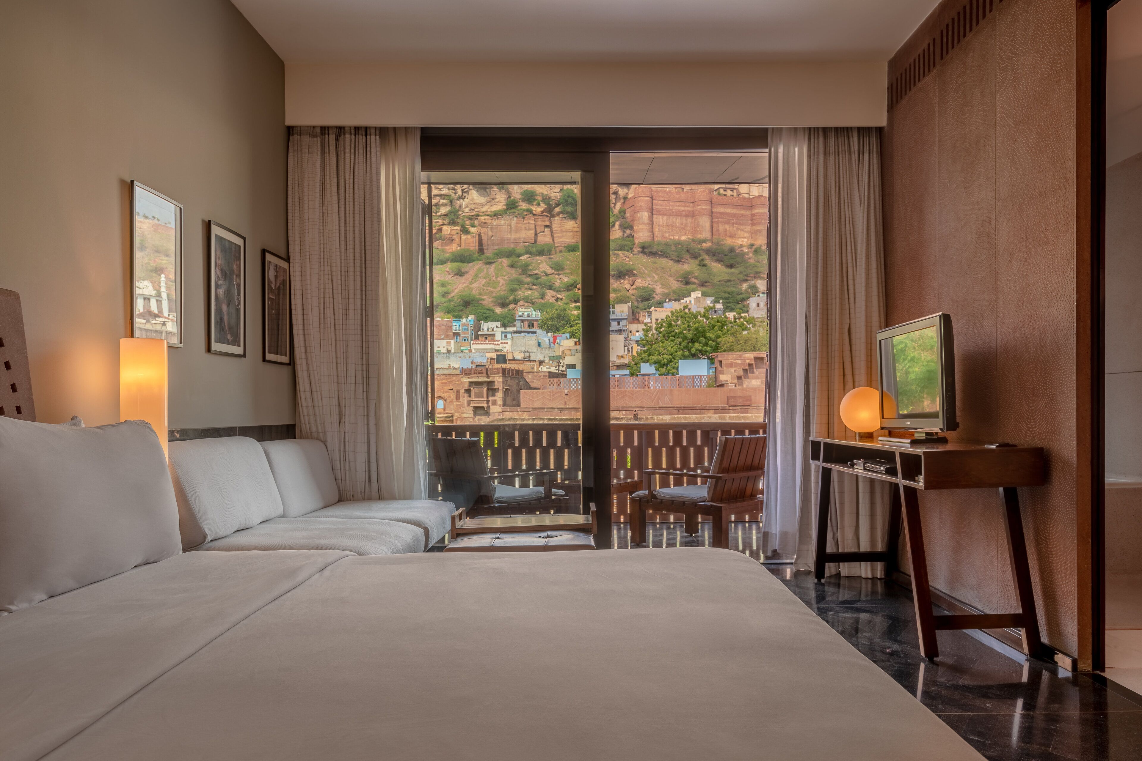 Habitación de hotel con una cama grande, televisión y balcón con vistas a la ciudad.
