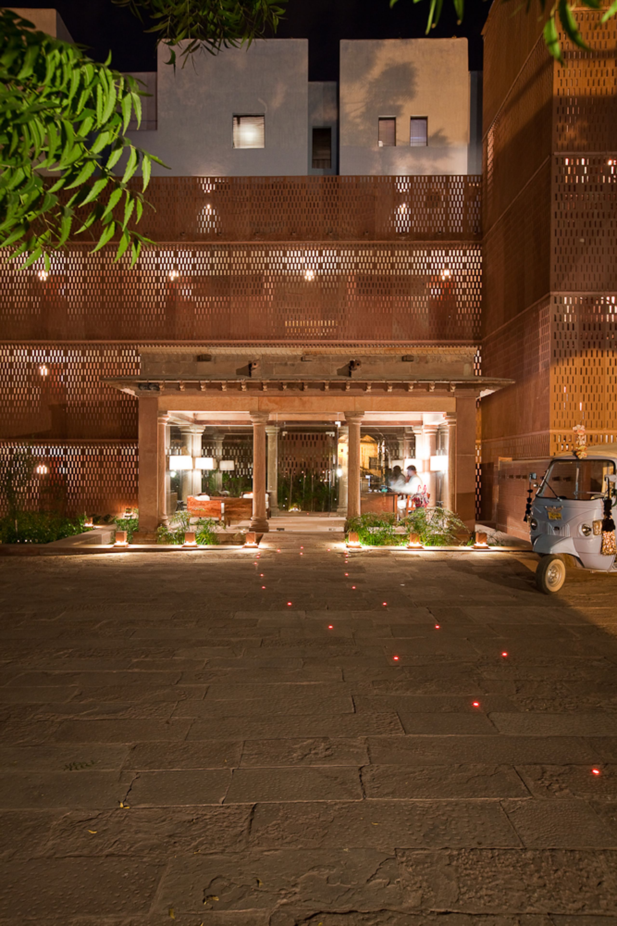 A building with a covered entrance, a small vehicle, and decorative lights.