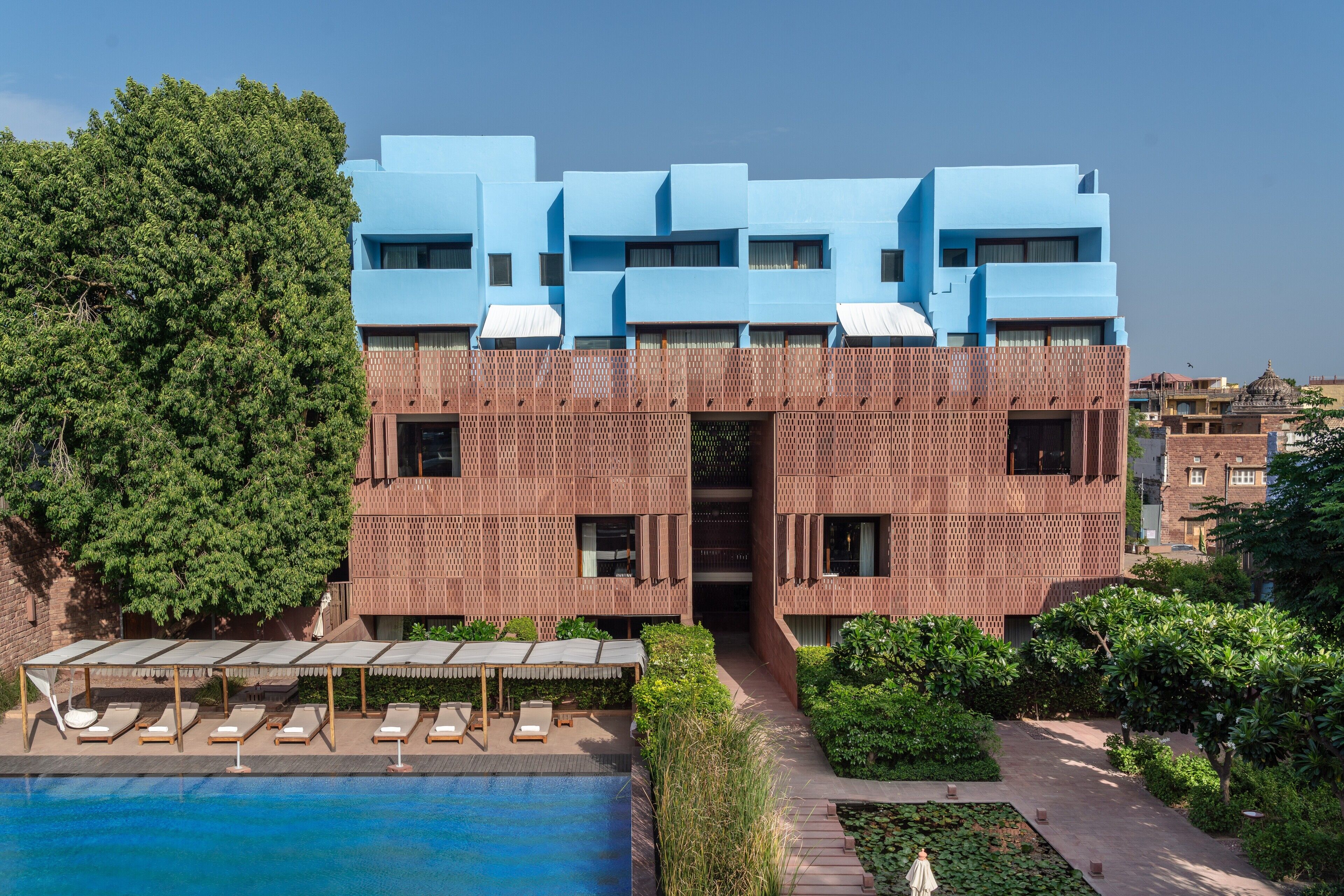 A modern building with a pool and sun loungers.