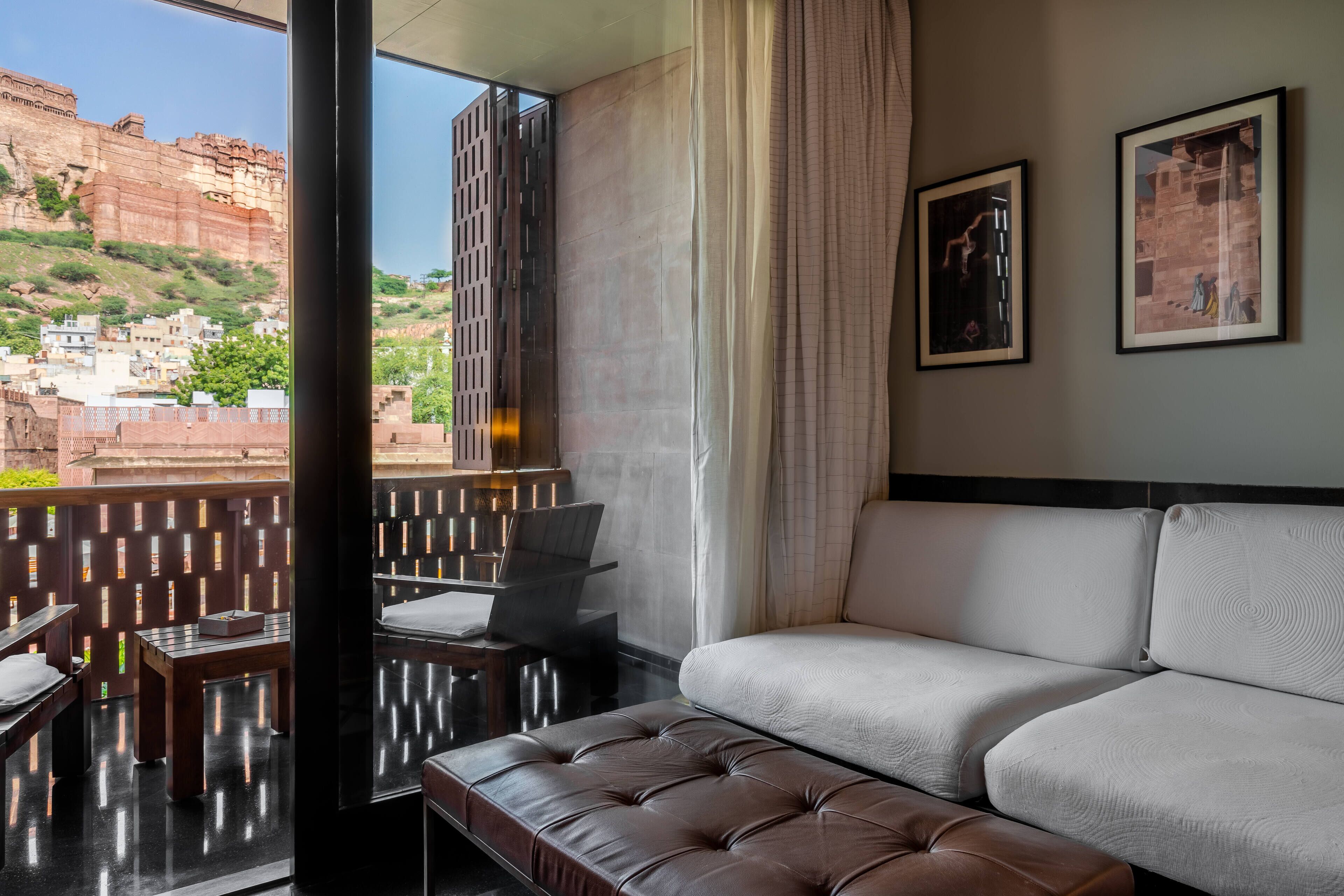 Quarto de hotel moderno com varanda, um sofá, uma mesa e duas fotos emolduradas na parede.