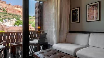 Quarto de hotel moderno com varanda, um sofá, uma mesa e duas fotos emolduradas na parede.