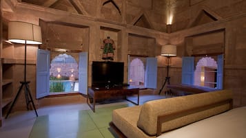 Traditional room with a large bed, flat-screen TV, and two windows offering views of the surrounding greenery.