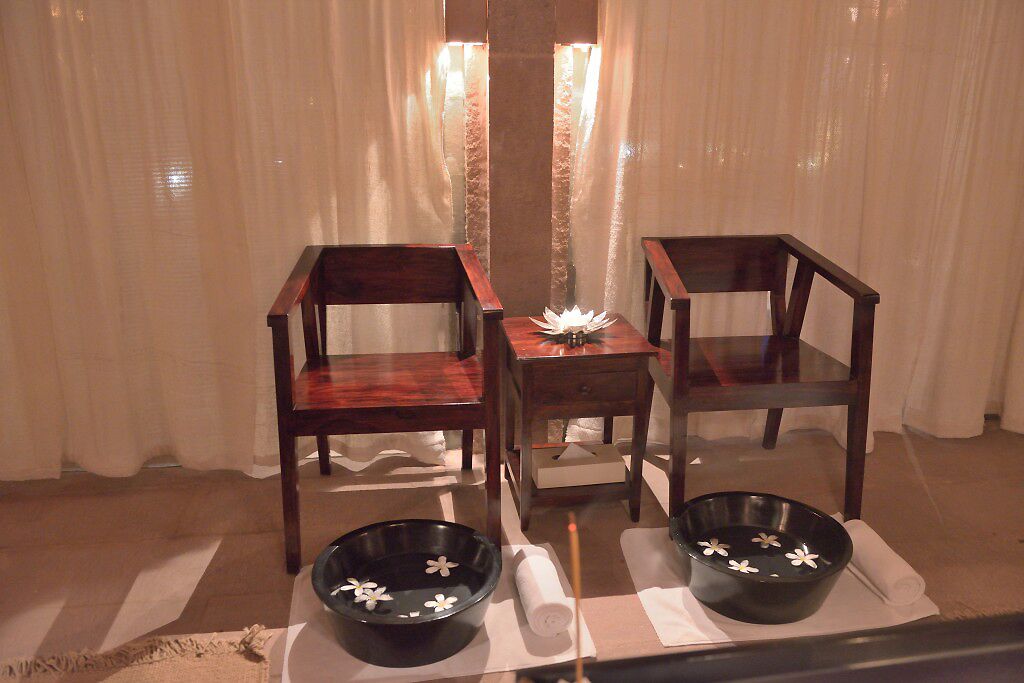 A room with two wooden chairs, a small table, and two black bowls with white flowers on a checkered mat.