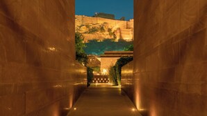 A corridor with stone walls and a pathway leading to a distant structure. - RAAS Jodhpur (Jodhpur)