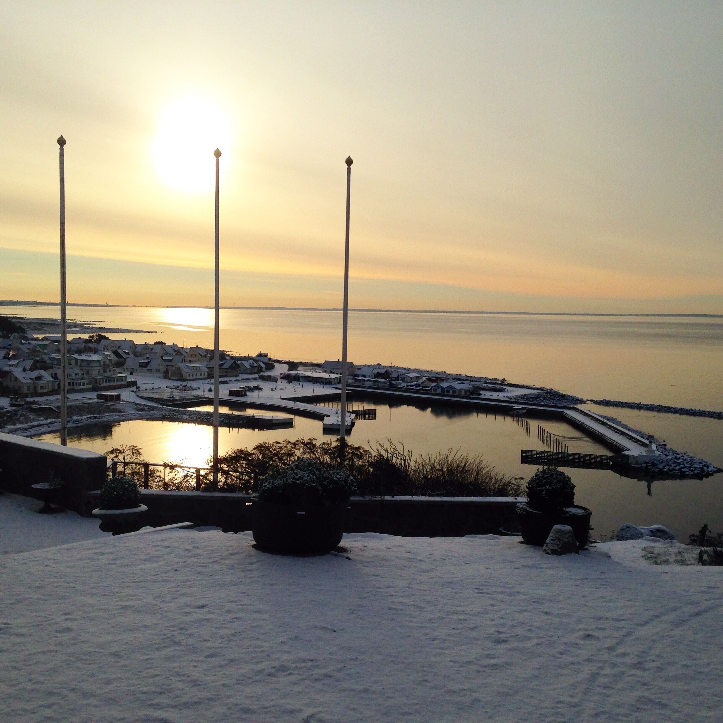 Ein Yachthafen mit ruhigem Gewässer, umgeben von schneebedeckten Gebäuden und einem klaren Himmel.