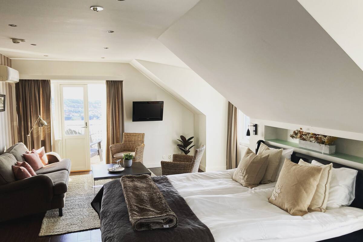 Une chambre moderne avec un grand lit, un canapé, une table à manger et un téléviseur fixé au mur.