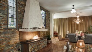 Un salon chaleureux avec une cheminée en briques, des meubles en osier et un lustre.