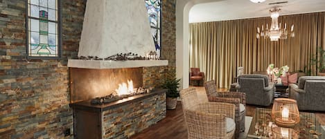 A cozy living room with a brick fireplace, wicker furniture, and a chandelier.