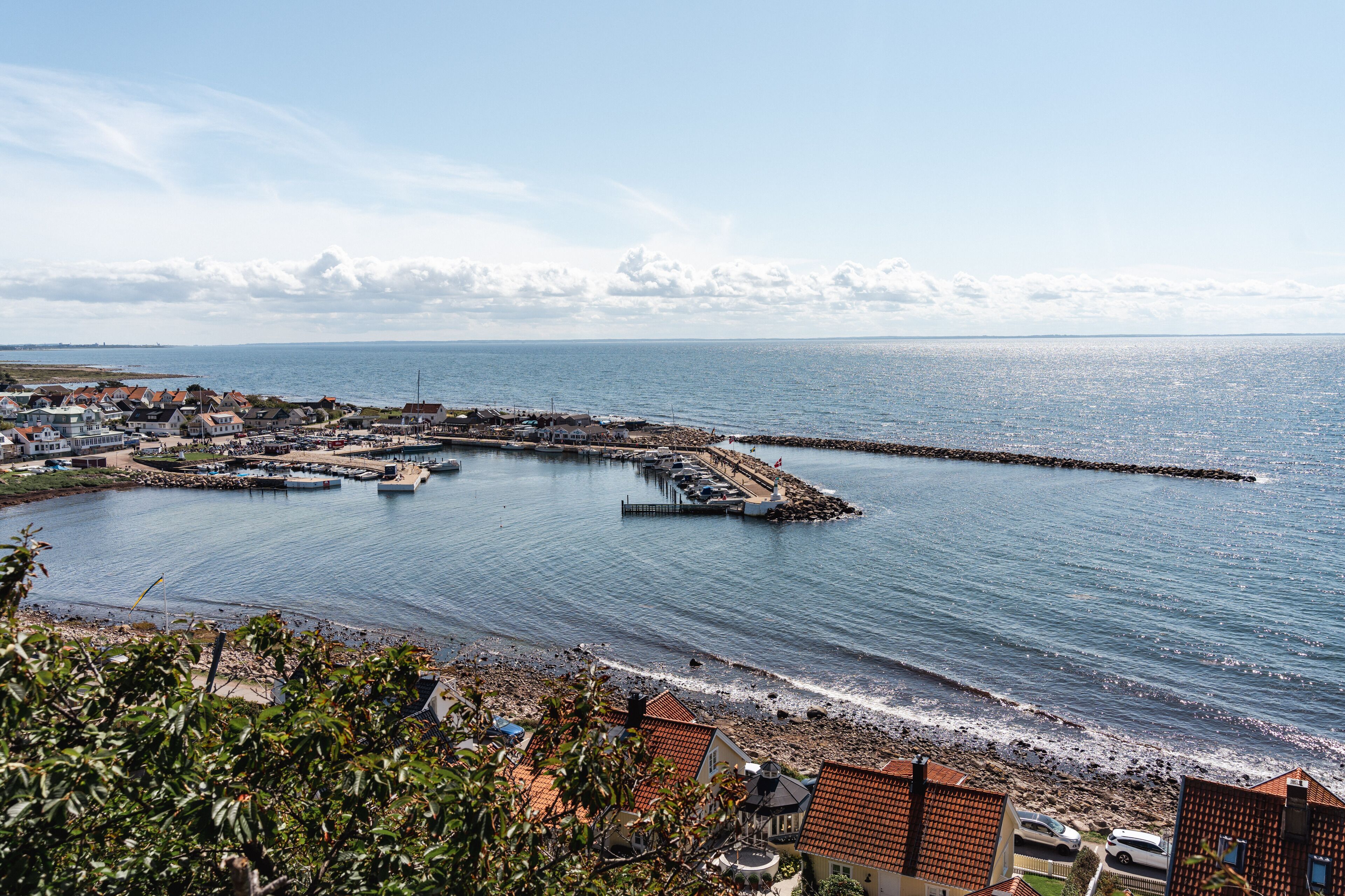 A coastal town with a marina, houses, and a rocky shoreline.