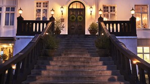 Un hôtel de luxe, doté d’une entrée imposante, d’un escalier menant aux portes principales et d’un balcon agrémenté de balustrades.