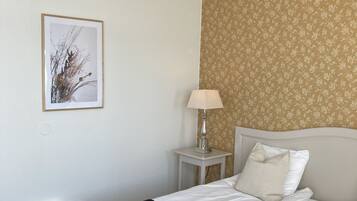 A hotel room with a bed, a nightstand, a lamp, and a framed picture on the wall.