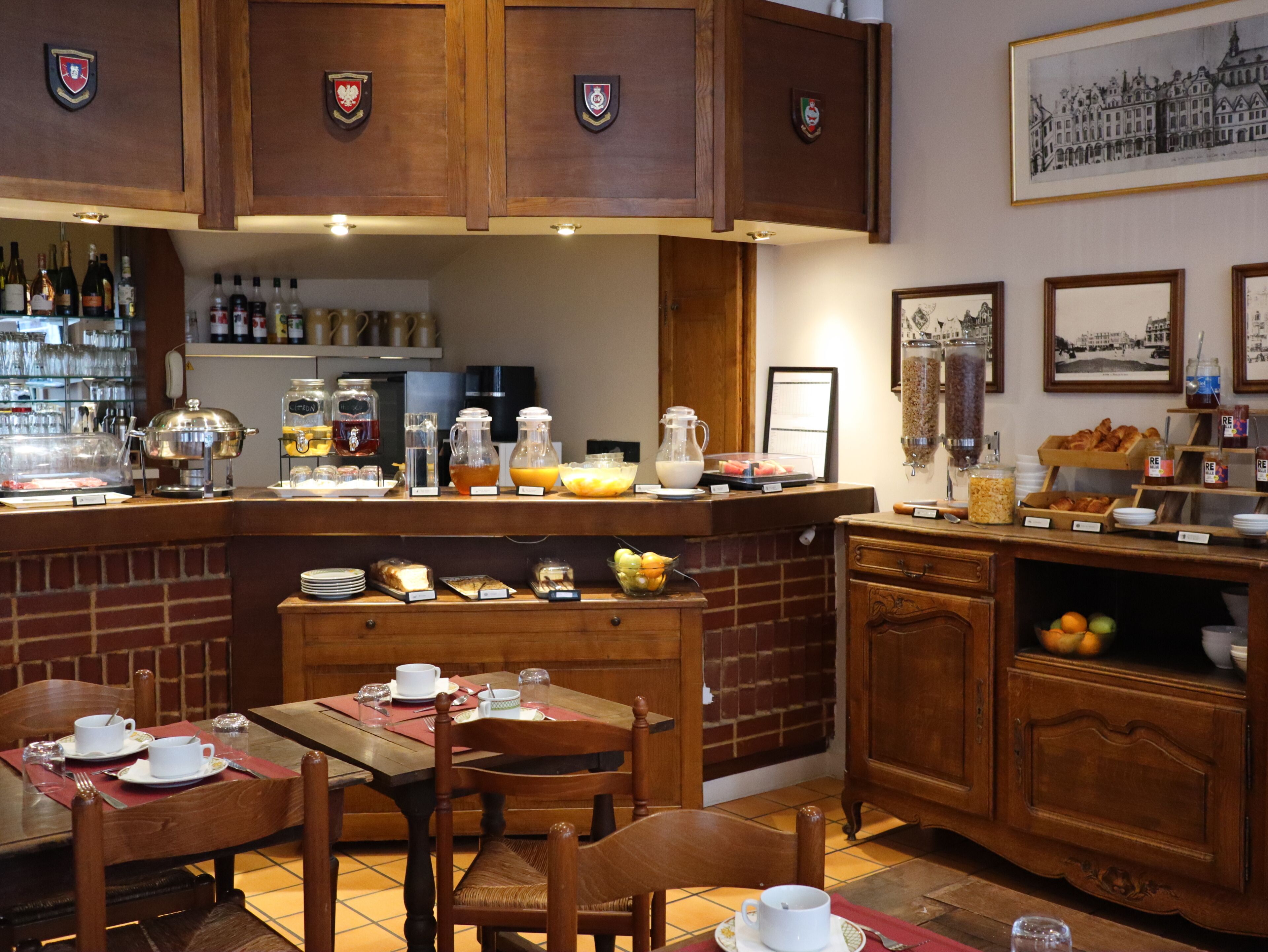 Un bufé de desayuno con diversos alimentos y bebidas, mobiliario de madera y una pared de ladrillo.