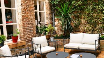 An outdoor seating area with brick walls, potted plants, and a large green plant in the center.