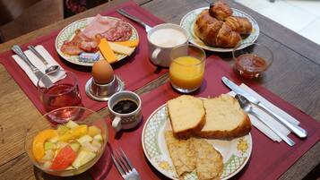 A breakfast table with plates of food, a fruit bowl, a glass of orange juice, and a cup of coffee.