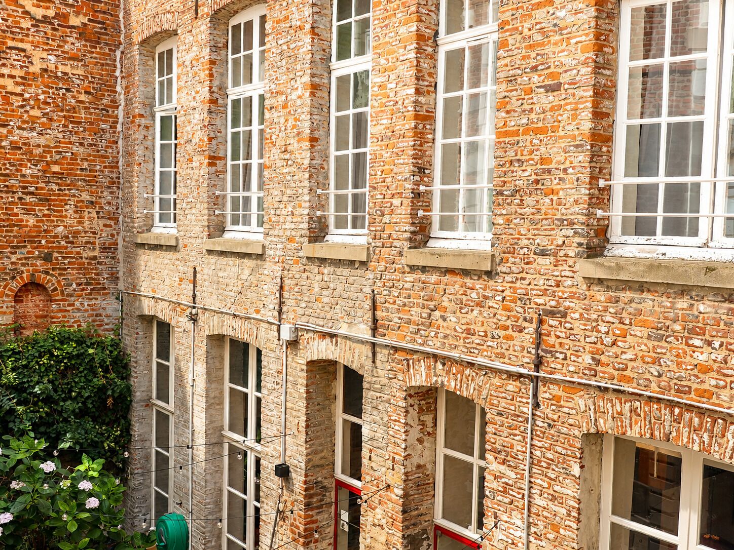 Un edificio de varios pisos de ladrillo con varias ventanas y un balcón visible.